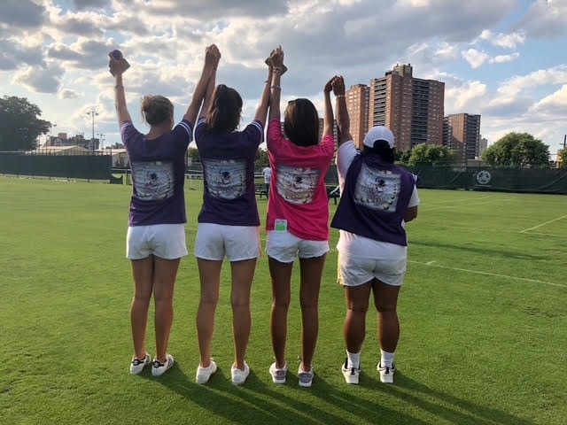 Four players with arms raised on the grass court at West Side Tennis Club